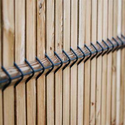 Lames de clôture bois insérées dans les mailles d'un panneau rigide