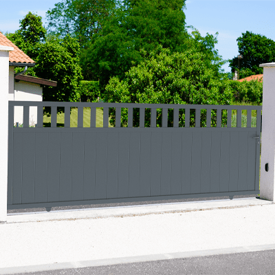 Portail coulissant ajouré en aluminium clôturant un jardin